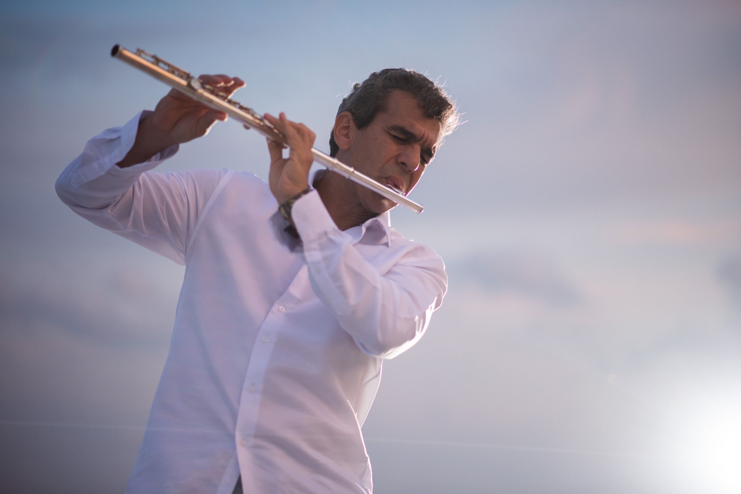 Huáscar Barradas tocando la flauta, fotografiado desde abajo contra un cielo abierto.