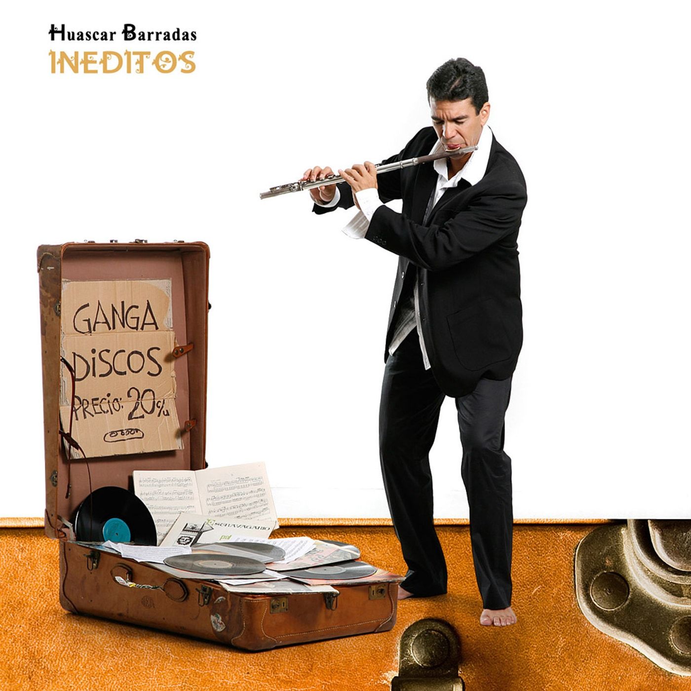 Portada de Inéditos: Huáscar Barradas de cuerpo entero, de traje negro y descalzo, tocando la flauta junto a una maleta llena de discos.